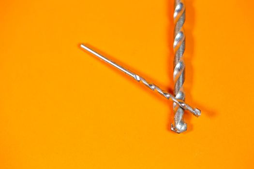 Drills for metal of different sizes for a drill on an orange background. Building tool