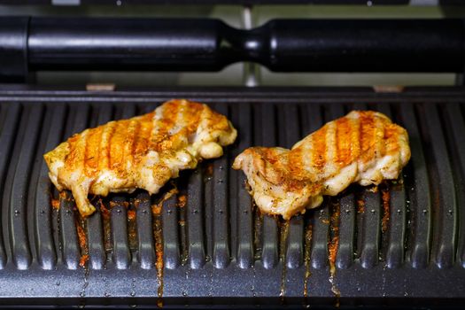 grilled chicken with spices on the electric grill in the home kitchen