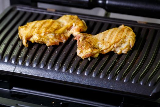 grilled chicken with spices on the electric grill in the home kitchen