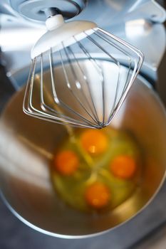 Beating eggs with sugar in a kitchen machine. Cream nozzle