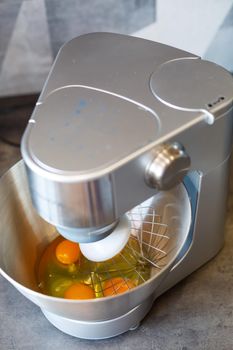 Beating eggs with sugar in a kitchen machine. Cream nozzle