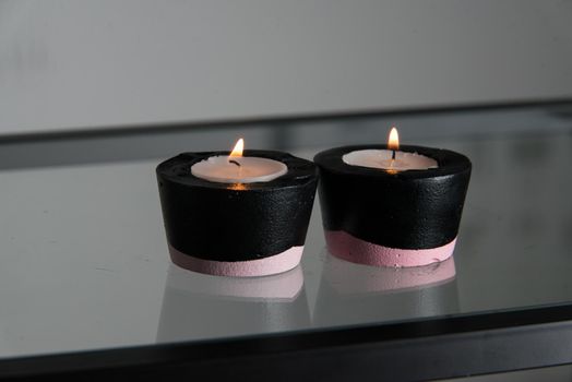 Two candles in black and pink concrete candle holders.