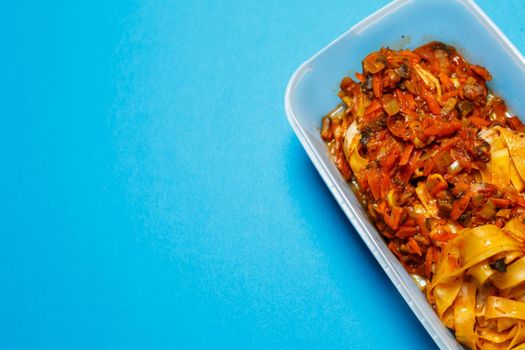 Braised pasta with vegetables in a plastic tray. Lunch for the office worker