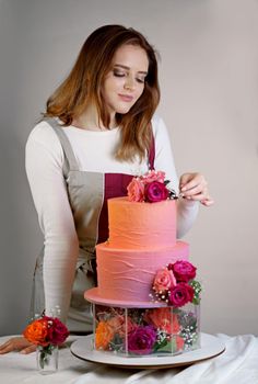 Confectioner in a working apron decorates a birthday cake with fresh flowers