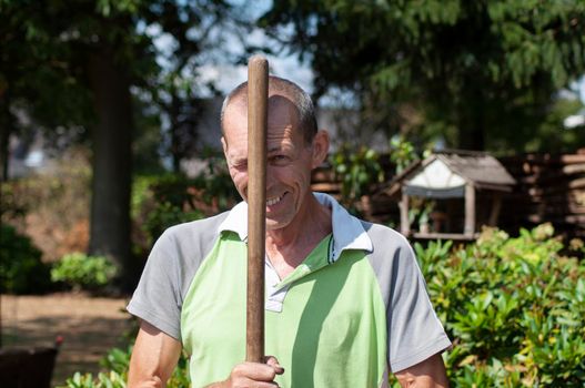gardener in dirty work clothes and boots holds garden tools, pitchforks, seasonal spring work in the vegetable garden. High quality photo