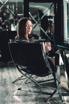 Portrait of young beautiful woman relaxing in a chair in a bathrobe with a detox drink in a hand. Luxery spa center. look at the camera