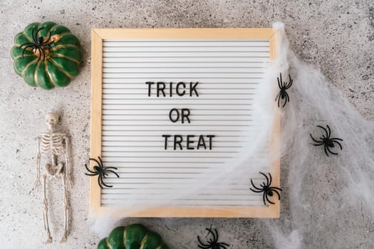 Happy halloween holiday concept. Skeletons, spider, web, pumpkin, trick or treat text on board frame on concrete grey background. Halloween festival, greeting card