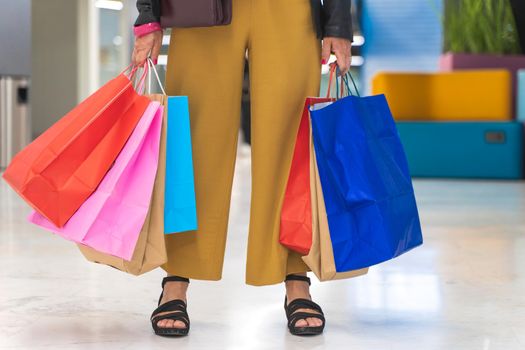 Unrecognizable woman with colorful shopping bags in the mall. High quality photo