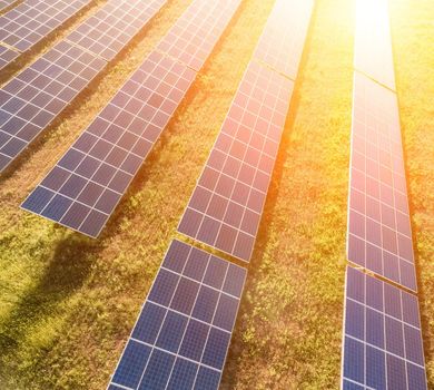Aerial top view of a solar panels power plant. Photovoltaic solar panels at sunrise and sunset in countryside from above. Modern technology, climate care, earth saving, renewable energy concept