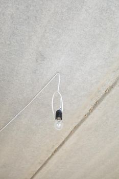 Light bulb on the ceiling. Lonely light bulb and wire sticking out of the ceiling during a repair