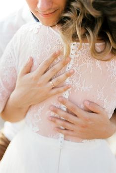 Hands of the groom on the back of the bride in a white lace dress. Cropped. High quality photo