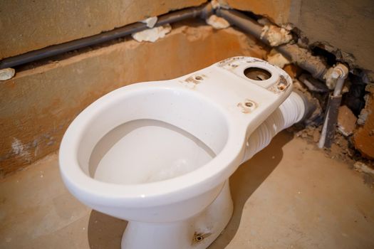 Installing a new toilet in the bathroom during repair work. Bathroom during finishing work. Installation of plumbing, faucets, plumbing and sewage