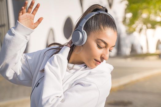 Young beautiful girl dancing happy in the street with headphones. High quality photo