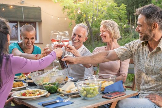 Happy friends laughing with big smile and toasting in a summer outside diner. Smiling people eating at house patio. Smiles, cheerfulness concept. High quality photo