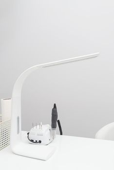 Manicure Studio. White lamp on white table with nail tool