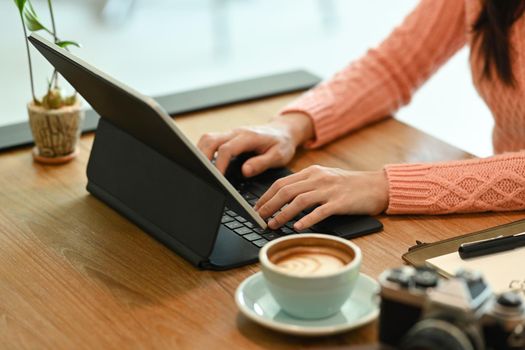 Close view woman in warm clothes working with computer tablet.