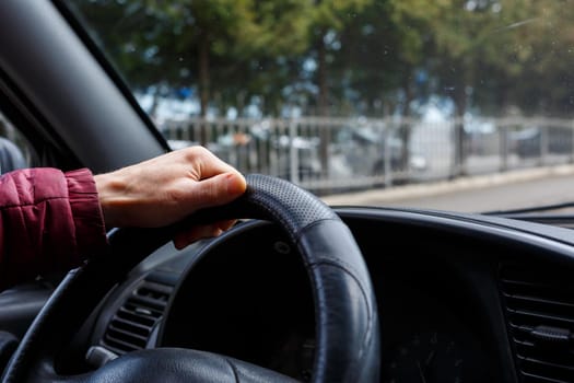 Male hand hold steering wheel in black leather, Man driving, transport concept,