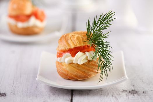 Profiteroles stuffed with cream cheese and salmon, decorated with a sprig of dill. Close-up 