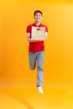 Delivery employee man hold brown craft paper bag for takeaway and jumping 