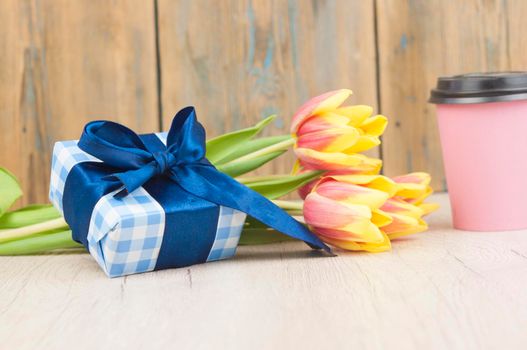 Composition with tulips, coffee cup and gift box on wooden table.