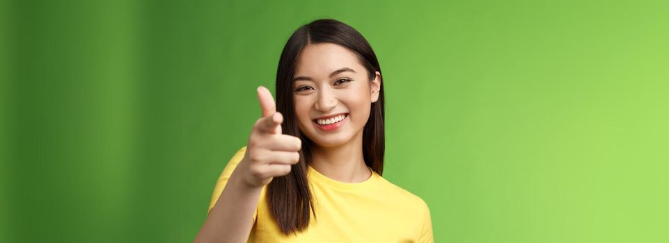 Close-up entertained outgoing asian brunette female having fun congratulate you, pointing you camera laughing, joyfully chat, having friendly conversation, gree background. Copy space