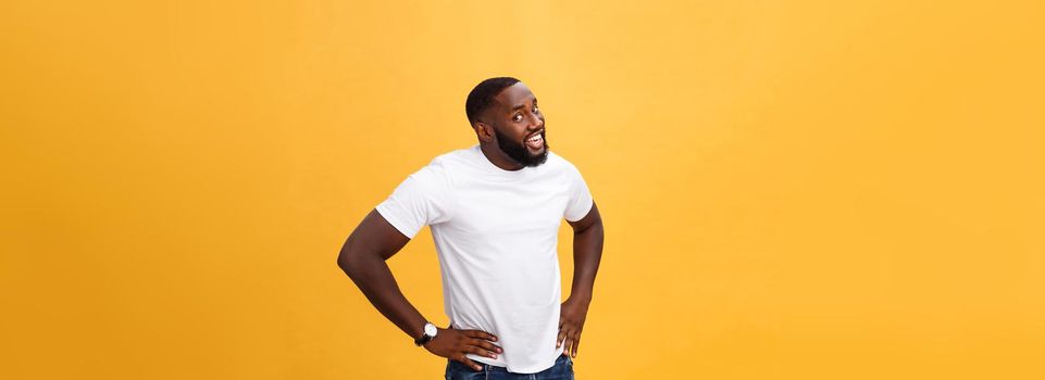 Portrait of handsome young african guy smiling in white t-shirt on yellow background.