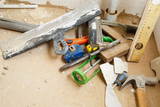 Tools for construction and repair lie on the concrete floor during repair work with a spatula, hammer, tape measure. To make repairs. Selective focus