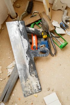 Tools for construction and repair lie on the concrete floor during repair work with a spatula, hammer, tape measure. To make repairs. Selective focus