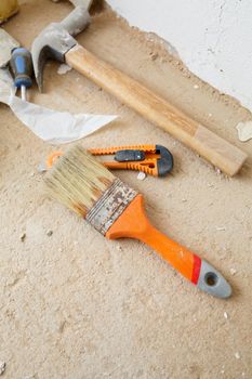 Tools for construction and repair lie on the concrete floor during repair work with a spatula, hammer, tape measure. To make repairs. Selective focus