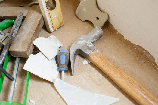 Tools for construction and repair lie on the concrete floor during repair work with a spatula, hammer, tape measure. To make repairs. Selective focus