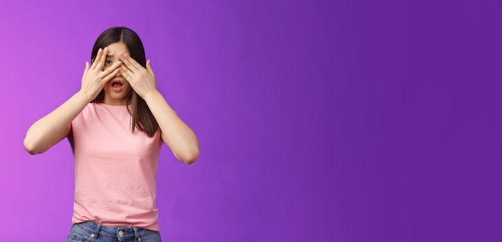 Shocked concerned asian girl witness terrible crime feel insecure scared, close eyes frightened shook, open mouth, gasping upset, standing stupor drop jaw, pose purple background. Copy space