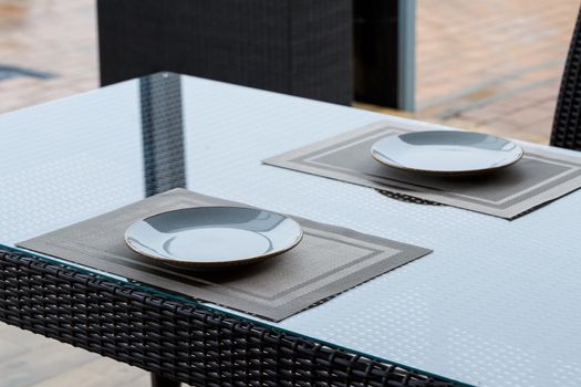 Served table in a restaurant for two. Blue plates for food, two glasses. Romantic evening concept