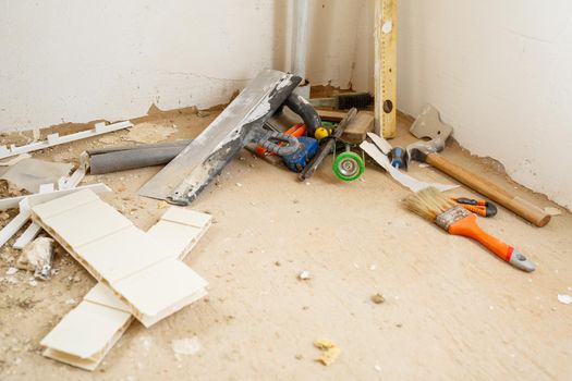 Tools for construction and repair lie on the concrete floor during repair work with a spatula, hammer, tape measure. To make repairs. Selective focus
