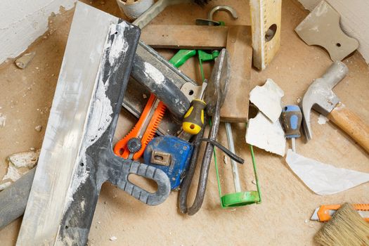 Tools for construction and repair lie on the concrete floor during repair work with a spatula, hammer, tape measure. To make repairs. Selective focus