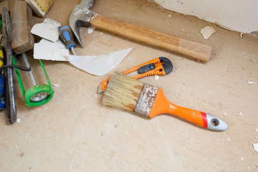 Tools for construction and repair lie on the concrete floor during repair work with a spatula, hammer, tape measure. To make repairs. Selective focus