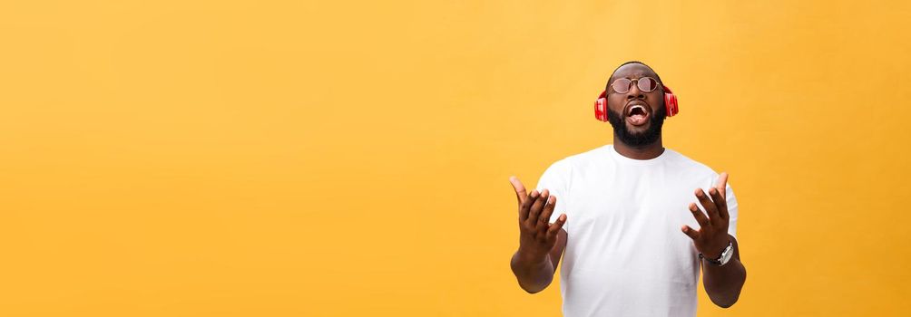 Young African American man wearing headphone and enjoy music over yellow gold Background.