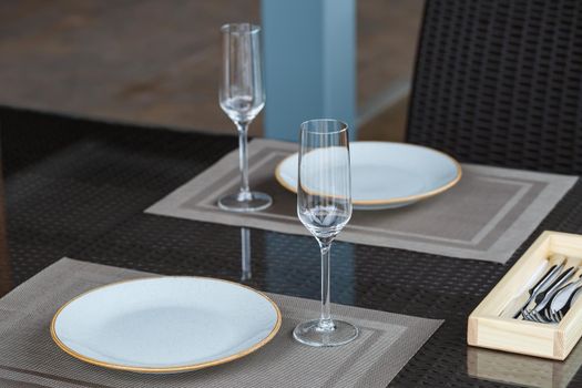 Served table in a restaurant for two. Blue plates for food, two glasses. Romantic evening concept