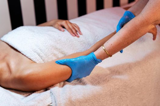 unrecognizable young woman relaxes lying on the beauty salon couch while receiving a relaxing arm massage, concept of body care and wellness