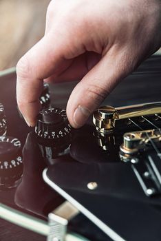 Male hand changing electric guitar settings. Tuning a timbre regulator. Close-up view