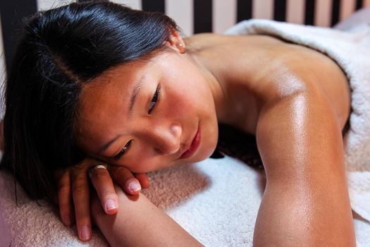 portrait of a beautiful young woman relaxes lying on the couch after a relaxing massage in the beauty salon, concept of body care and wellness
