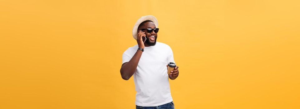 Handsome African American with mobile phone and take away coffee cup. Isolated over yellow gold background