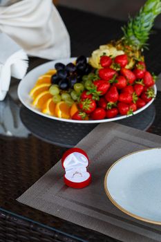 Engagement gold precious jewelry ring for a girl in a red box on a background of fruit