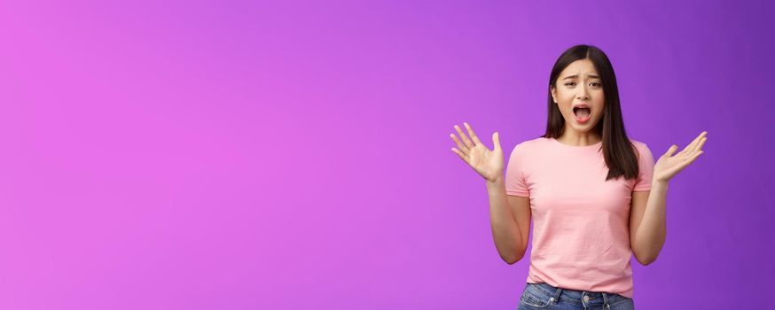 Complaining arrogant asian girlfriend whining cruel world, yelling crying being nasty, spread hands sideways bothered, feel unfair and displeased, look offended, stand purple background.