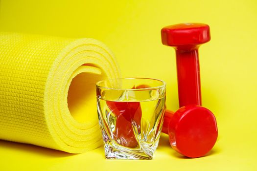 red dumbbells, a glass of water, a yellow rug, colored background, sports, energy drink, equipment for the gym