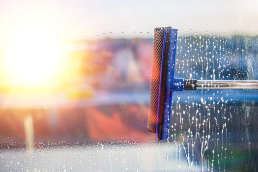 Window cleaning brush. Large window in a multi-storey building, cleaning service. Window cleaning in high-rise buildings, houses with a brush. Dust removal and glass washing.