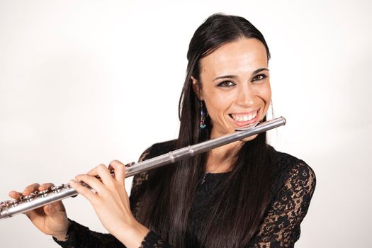 Close up portrait of a young elegant female flutist looking at camera and smiling with joy