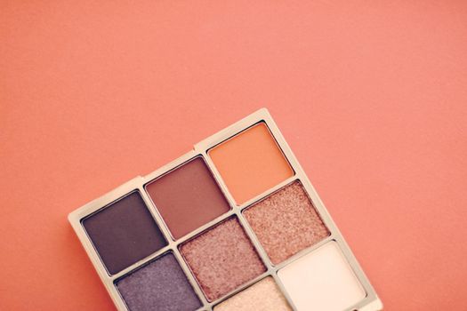 Cosmetic branding, mua and girly concept - Eyeshadow palette and make-up brush on orange background, eye shadows cosmetics product as luxury beauty brand promotion and holiday fashion blog design