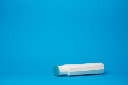 white bottle with cream, hair shampoo, shower gel, isolated blue background, human body beauty