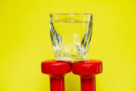 red dumbbells, a glass of water, colored background, sports, energy drink, equipment for the gym