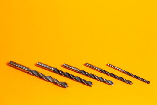 Drills for wood of different sizes for a drill on an orange background. Construction tool